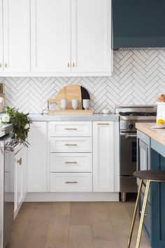 a kitchen with white cabinets and blue counter tops, gold accents on the backsplash