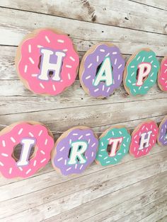 decorated doughnuts with happy birthday spelled out in front of them on a wooden wall