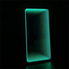 a mirror that is lit up in the dark with green lines on it's sides