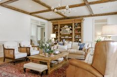 a living room with couches, chairs and a coffee table in front of a bookcase