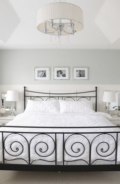 a bed with white sheets and pillows in a bedroom next to pictures on the wall