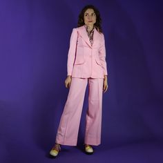 Fabulous vintage 1970s handmade two piece suit. Pastel pink polyester which holds it's shape so beautifully. Cut with a wide lapel blazer, faux pocket tabs and matched with a pair of high waisted button tab flares. Such a fabulous colouway in classic 70s cut! Best fit UK 6-8 Chest: 34" Shoulder:15" Length:28" Waistband: 27" Rise:12" Hip:36" Inside leg:31" extra2.25" inside) Tailored Pink Blazer With Pockets, Pink Tailored Blazer With Pockets, Pink Notch Lapel Suit With Pockets, Pink Notch Lapel Suits With Pockets, Fitted Pink Pantsuit With Pockets, Pink Notch Lapel Pantsuit With Pockets, Pink Blazer With Suit Collar And Pockets, Pink Blazer With Pockets And Suit Collar, Tailored Pink Blazer With Notch Lapel