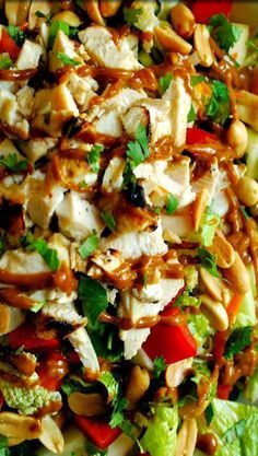 a salad with chicken, lettuce, tomatoes and nuts in it on a plate