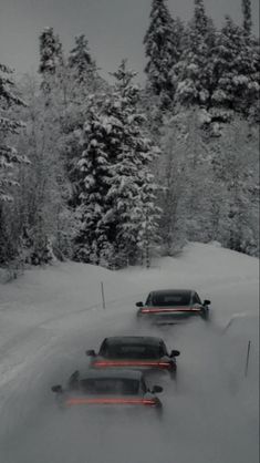 three cars driving down a snowy road with trees in the back ground and snow on the ground