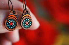 a close up of a person holding some kind of earring in their hand with red and blue designs on it