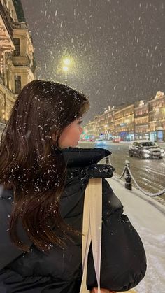 a woman standing in the snow with her back to the camera and looking at something