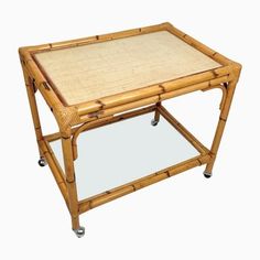 a bamboo coffee table with wheels on the bottom and a glass top in the middle