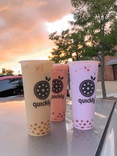 three drinks sitting on top of a table next to each other in front of a tree