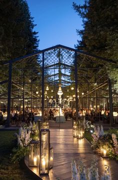 an outdoor wedding venue lit up at night with candles on the walkway and flowers in the foreground