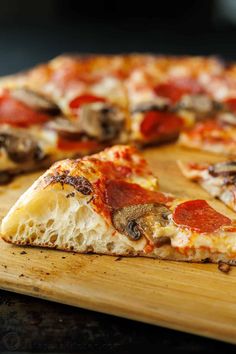 a close up of a pizza on a cutting board with one slice missing from it