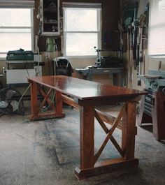 a workbench in a garage with tools on the table and two windows behind it