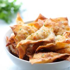 a white bowl filled with cheesy tortilla chips next to some parsley