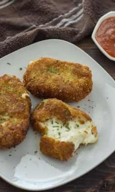 three fried food items on a white plate with sauces and cloth in the background