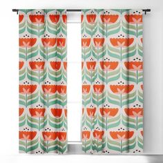 an orange and green floral curtain hanging in front of a window with the curtains open