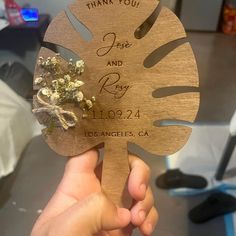 a person holding up a wooden fan with flowers on the front and back of it