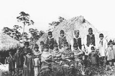 a group of people standing next to each other in front of a thatched hut