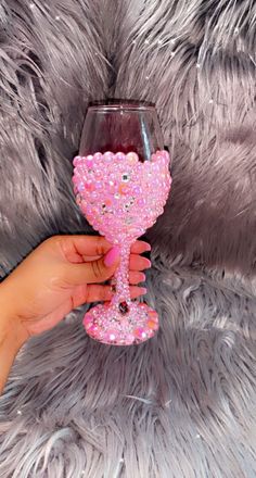 a hand holding a wine glass with pink glitter on it