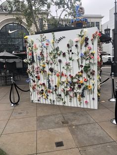 an art piece made out of flowers on the side of a building in front of a cafe