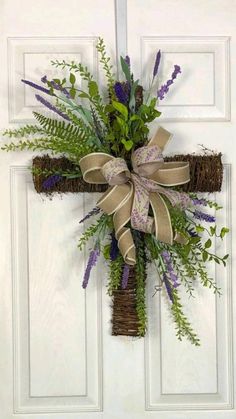 a cross made out of grass and flowers hangs on the front door