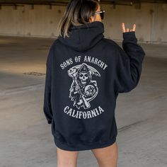 SOA Hoodie, SOA Fan gift, Jax Teller Hoodie, Reaper Crew hoodie, SOA merch, Sons Hoodie, Jax Teller fan gift, Jax teller merch ⭐️Gildan Brand  ⭐️Unisex Adult Sizing ⭐️100% Cotton ⭐️DTG (Direct to Garment) printing, meaning the ink is directly printed into the fabric CARE: ⭐️Wash inside out ⭐️Machine wash Cold. Tumble dry" medium heat Sizing:  ⭐️Please reference the sizing chart listed in photos before purchasing  ⭐️The model in the photo is wearing a XL ⭐️If you want an oversized fit, please ord Winter Fan Apparel Hoodie With Screen Print, Casual Hooded Hoodie For Fan Merchandise, Casual Sweatshirt With Adjustable Hood For Fans, Casual Hoodie With Front And Back Print For Winter, Band Merch Crew Neck Hoodie For Fan Merchandise, Band Merch Crew Neck Hoodie For Fans, Band Merch Hoodie For Fan Merchandise In Winter, Winter Band Merch Hoodie For Fans, Casual Fleece Hoodie For Fan Merchandise