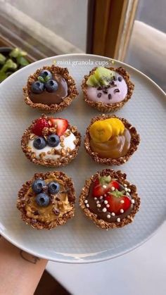 a white plate topped with mini desserts on top of a table next to a window