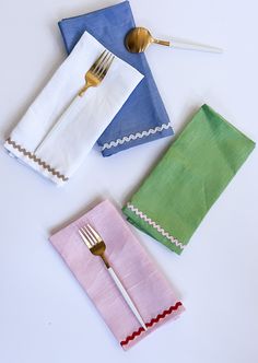 three napkins and two forks on a white table