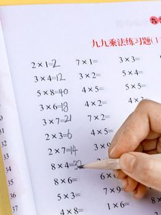 someone is writing on a piece of paper with numbers written in chinese and two hands are holding a pencil