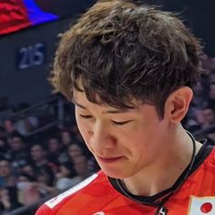 the young man is looking at his cell phone in front of an arena full of people