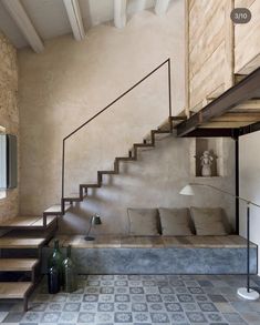 a living room filled with furniture next to a stair case on the side of a wall