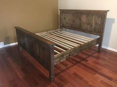 a bed frame made out of wood in a room with hard wood floors and walls