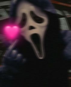 a ghost holding a pink heart in its mouth