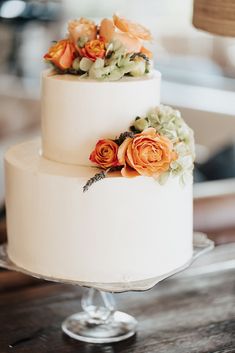 a three tiered white cake with orange flowers on top