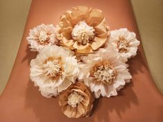 paper flowers arranged on top of each other in the shape of a flower bouquet, against an orange background