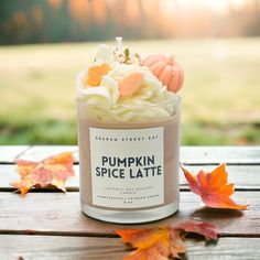 a pumpkin spice latte in a jar on a wooden table with fall leaves around it