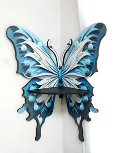 a blue and white butterfly shaped clock mounted to the side of a wall