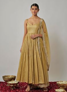 This stunning Champagne Gold Sequin Embroidered Anarkali Set embodies elegance and timeless sophistication. Crafted from lightweight georgette, this champagne anarkali is beautifully adorned with intricate sequin and gold threadwork, offering a hint of glamour and shine. The fitted bodice with a wide neckline and delicate noodle straps creates a flattering, modern silhouette, while the flowing pleated skirt adds grace. Paired with a matching lycra churidar, this set is completed with a gold soft net dupatta, featuring an exquisite scalloped sequin border and scattered butti embroidery. Perfect Anarkali for Sangeet, weddings, or festive celebrations. Composition : Anarkali - Viscose Georgette, Dupatta - Soft Net and Churidar - Lycra Care: Dry Clean Only and Vacuum Storage This product can b Gold Anarkali Set, Gold Anarkali Salwar Kameez, Gold Anarkali Set With Traditional Drape, Gold Anarkali Set For Eid, Gold Floor-length Anarkali Set With Sheer Dupatta, Festive Gold Anarkali Set, Gold Anarkali Set With Zari Work, Gold Designer Anarkali Set Maxi Length, Gold Anarkali Maxi Length Set