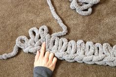 someone is crocheting something on the floor with their hands and fingers to make it look like an octopus