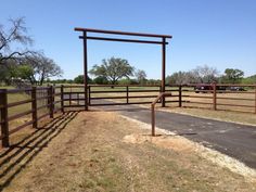 a gated in area with cars parked on the other side and dirt road next to it