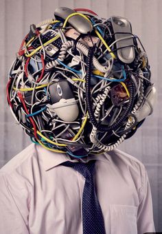 a man wearing a tie with lots of wires on his head in front of him