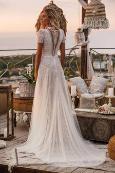 a woman in a wedding dress is standing on a deck with her back to the camera