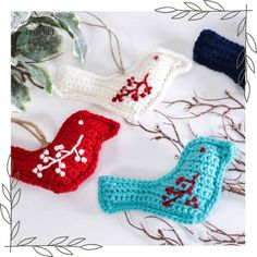 three crocheted boots sitting next to each other on a white surface with leaves and branches in the background