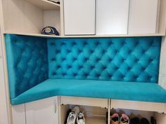 there is a blue bench in the corner with shoes on it and some cupboards