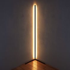 a light that is on in the middle of a room with wood flooring and white walls