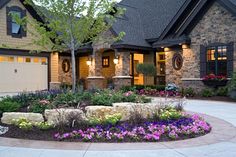 a house with flowers in the front yard and landscaping on the side walk around it