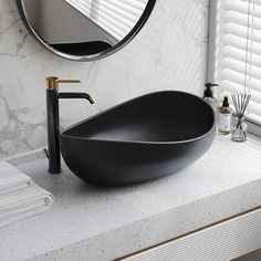 a black bowl sink sitting on top of a white counter next to a round mirror