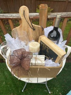 a basket filled with wine, cheese and other items sitting on top of a table