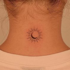 a woman's neck with a small sun and moon tattoo on the back of her neck