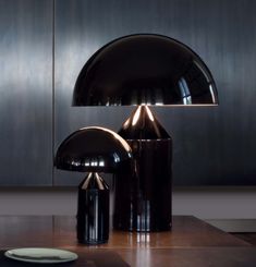 a black lamp sitting on top of a wooden table next to a plate and cup