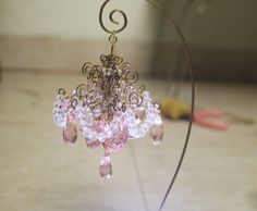 a pink chandelier hanging from a wire on a counter top next to a pair of scissors