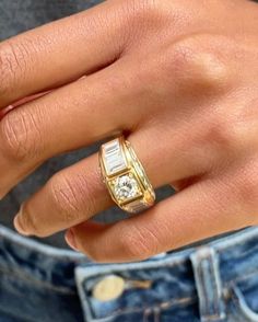 a person wearing a gold ring with a baguette cut diamond on it's side